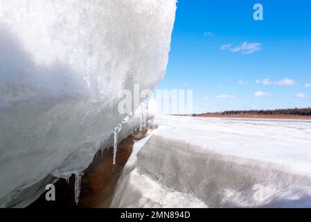 Frühlingseis mit Schnee schmilzt am Flussufer gegen den Himmel. Stockfoto