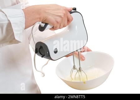 Eine Erwachsene Frau in weißer Koch-Kleidung kocht in einer Küche, isoliert auf weißem Hintergrund Stockfoto