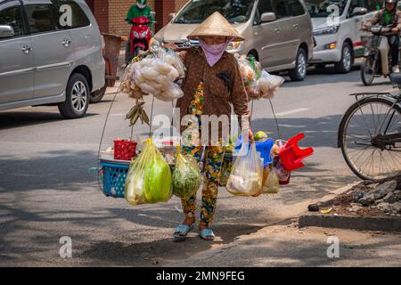 Straßenverkäufer mit traditionellen Schulterkörben und Taschen mit Produkten in Vietnam Stockfoto
