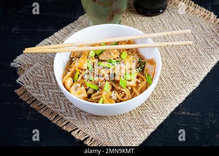 Nudeln mit Gemüse, Huhn und Pilzen in der Schüssel. Gebratene Pasta umrühren Stockfoto
