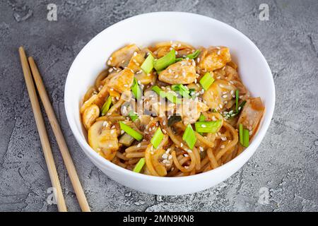 Nudeln mit Gemüse, Huhn und Pilzen in der Schüssel. Gebratene Pasta umrühren Stockfoto