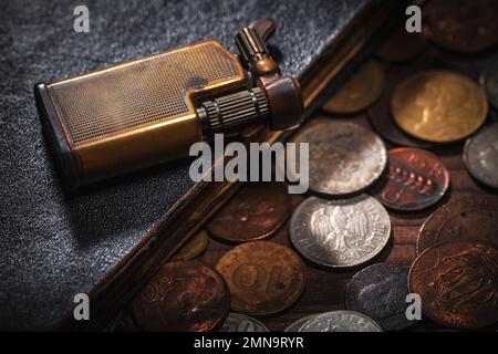 Alte Münzen aus der ganzen Welt und altes Buch, Feuerzeug Stockfoto