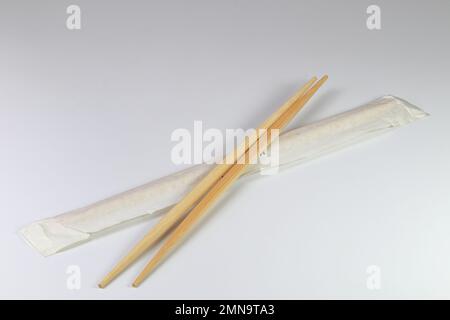 Gebrauchsfertige oder Einweg-Bambusstäbchen in Braun mit isolierter Verpackung auf weißem Hintergrund. Stockfoto