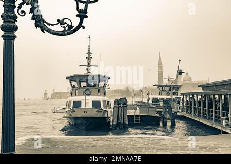 Blick auf die San Zaccaria Vaporetto Fähre Halt mit den Leuten, die an Bord des Bootes gehen, mit Campanile di San Giorgio im Hintergrund, Venedig, Italien. Stockfoto