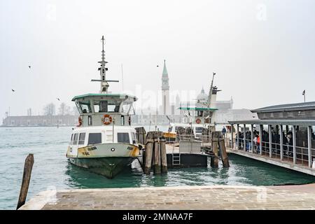 Blick auf die San Zaccaria Vaporetto Fähre Halt mit den Leuten, die an Bord des Bootes gehen, mit Campanile di San Giorgio im Hintergrund, Venedig, Italien. Stockfoto