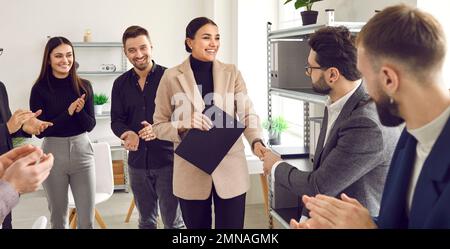 Team von Mitarbeitern, die Frau zu ihrer Beförderung gratulieren und Anerkennung für ihre Arbeit zeigen Stockfoto