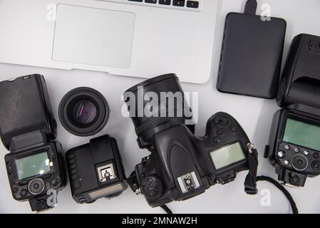 Draufsicht eines Fotografen mit Digitalkamera, Blitz, Reinigungskit, Speicherkarte, externer Festplatte, USB-Kartenleser, Laptop und Kamerazubehör Stockfoto