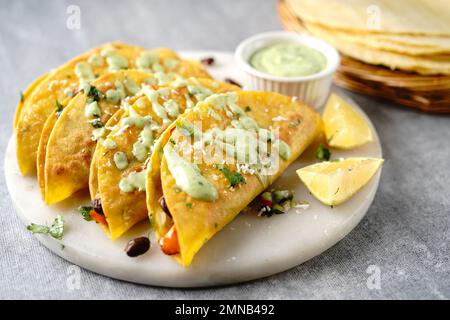 Knusprig gebratener Reis und Bohnen Tacos | Vorspeise für den Spieltag serviert mit Avacado-Sahne-Sauce Stockfoto