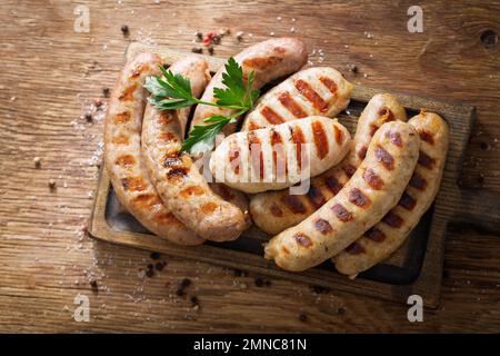 Gegrillte Würstchen auf einem Holzbrett, Draufsicht Stockfoto