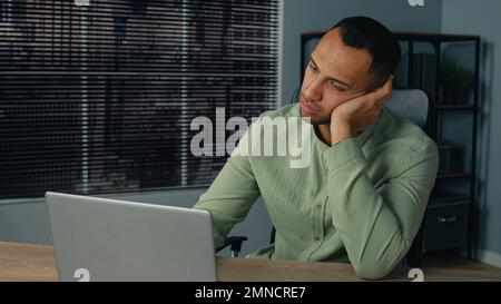 Müder, fauler, junger afroamerikanischer Geschäftsmann, der sich auf der Arbeit langweilt, schläft am Schreibtisch ein, ein überarbeiteter, ethnischer Angestellter, der am Arbeitsplatz schläft Stockfoto