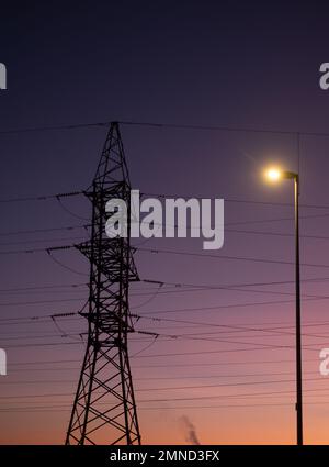 Stromnetz und Sonnenuntergang. Turm und Leitungen. Hohe Strom- und Energiemarktpreise. Hohe Strom- und Energiemarktpreise. Stockfoto