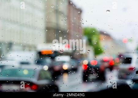 Schlechtes Wetter, Regen, Straßenverkehr durch nasses Glas fotografiert. Stockfoto