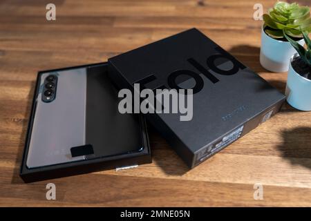 Samsung Galaxy Z Fold 4 in grau-grüner Farbe. Das Gerät befindet sich in der geöffneten Position. Originalverpackung auf den s Stockfoto