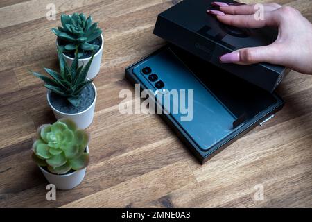 Samsung Galaxy Z Fold 4 in grau-grüner Farbe. Das Gerät befindet sich in der geöffneten Position. Originalverpackung auf den s Stockfoto