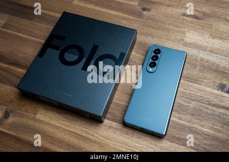 Brandneues Samsung Galaxy 4-Falz in Originalverpackung. Vor rotem Hintergrund. Stockfoto