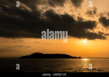 See bei Sonnenuntergang, bei Sonnenuntergang die Sonne geht von den Wolken herunter und reflektiert auf dem Wasser Stockfoto