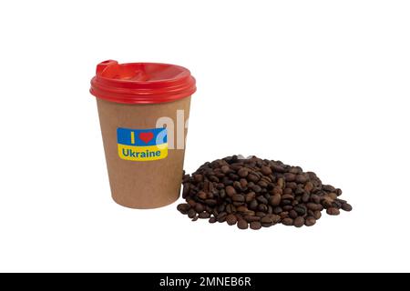 Pappbecher Kaffee mit einem patriotischen Aufkleber „I love Ukraine“ und einer Handvoll gerösteter Kaffeebohnen, isoliert auf weißem Hintergrund (Nahaufnahme) Stockfoto