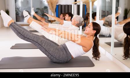 Personen unterschiedlichen Alters, die Pilates-Übungen im Fitnessstudio durchführen Stockfoto