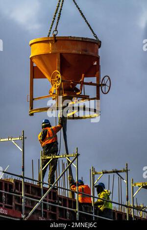 Betonarbeiten in der Dämmerung auf einer großen Baustelle, auf der ein Wohn- und Gewerbekomplex, NRW, Deutschland, errichtet wird; Stockfoto