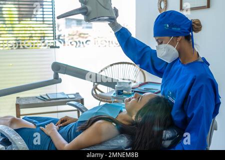 Eine junge Frau, die ihre Zähne beim Zahnarzttermin untersuchen lässt. Stockfoto