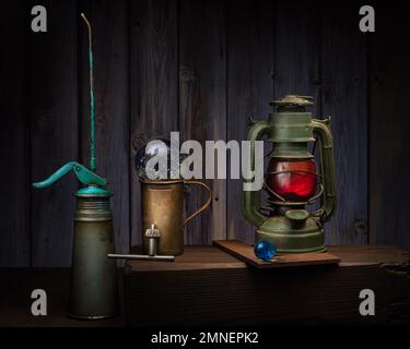 Stillleben mit alten Ölkannen. Glaskugeln, Paraffinlampe und Bohrfutterschlüssel, Studioaufnahme, dunkler Hintergrund Stockfoto