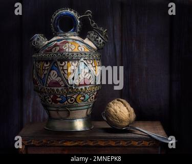 Stillleben mit orientalischem Gefäß und Walnuss auf Löffel, Studioaufnahme, dunkler Hintergrund Stockfoto