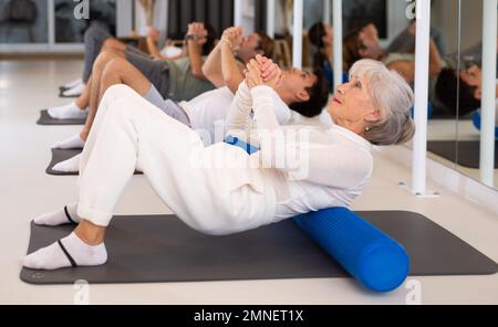 Gruppe von Personen, die im Fitnessstudio Hüftbrücken-Übungen machen Stockfoto