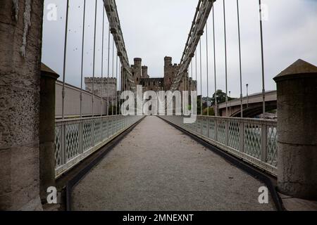 Thomas Telfords erste Hängebrücke 1826 über den Fluss Conwy in Nordwales verläuft parallel zur Schiene und zu neuen Straßenbrücken mit Conwy Castle dahinter Stockfoto