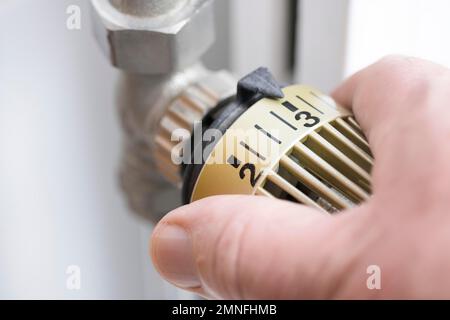 Die Hand dreht den Heizthermostat, Deutschland Stockfoto