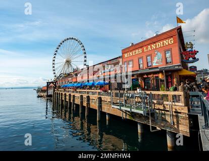 Waterfront, Miners Landing am Pier 57, hinter dem Riesenrad The Seattle Great Wheel, Seattle, Washington, USA Stockfoto