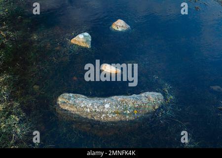 Ein natürliches Smiley aus Steinen inmitten einer Pfütze im Hochland Schottlands Stockfoto