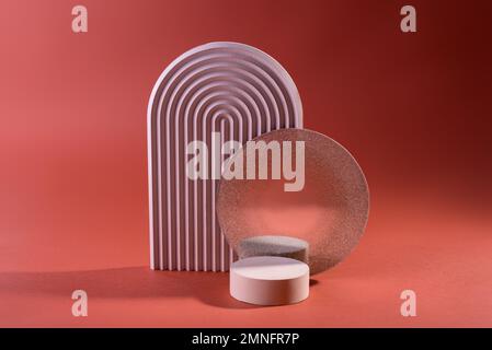 Zusammensetzung geometrischer Podien oder Sockel in schmutzigem Rosa gegen Rot. Minimaler Hintergrund für die Präsentation kosmetischer Mittel. Stockfoto