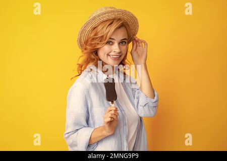 Portrait von fröhlichen lustigen Teenager-Mädchen genießt den Verzehr von kalten gefrorenen Dessert, isst köstliche Schokolade Eis, gelber Hintergrund. Stockfoto