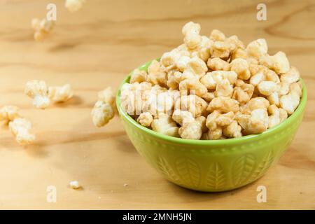 Eine Schüssel mit leckerem karamellisiertem Popcorn; auf Holzhintergrund. Stockfoto