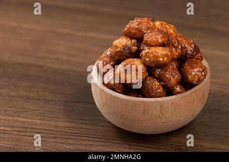 Holzschüssel mit kandierten organischen Erdnüssen - Hypogaea de Arachis. Stockfoto