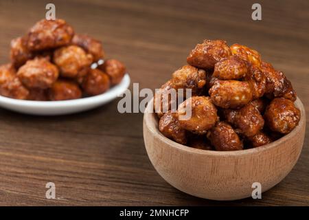 Holzschüssel mit kandierten organischen Erdnüssen - Hypogaea de Arachis. Stockfoto