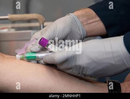 Ein Krankenhausarzt der Klasse 2., der dem Flottenchirurgenteam (FST) 4 zugewiesen ist, nimmt Blut von einem Techniker für Luftfahrt-Support-Ausrüstung 3. Klasse Ca. 2020 Stockfoto