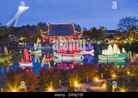 Beleuchtete chinesische Junks-Laternen und Friendship Hall-Pavillon am Dream Lake während der jährlichen Ausstellung Magic of Laternen im Chinesischen Garten in der Abenddämmerung. Stockfoto