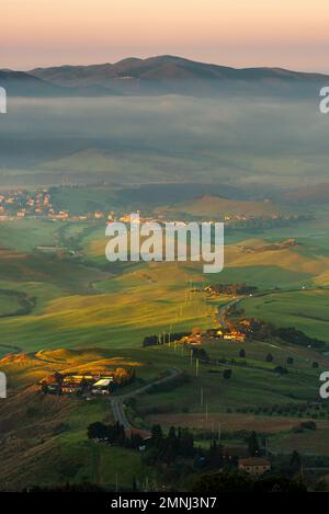Sanfte grüne Hügel und Felder mit frühmorgendlicher Sonneneinstrahlung auf den Hügeln in der Nähe von Volterra, Toskana, Italien Stockfoto
