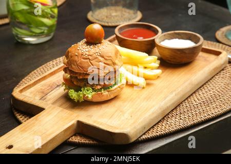 Kleiner Burger, serviert mit pommes Frites und Saucen auf dem Holzbrett im Café Stockfoto