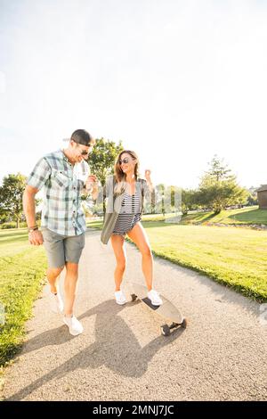 Lächelndes Paar mit Skateboard im Park Stockfoto