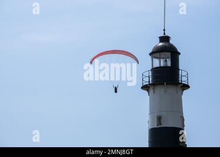 Leuchtturm und Gleitschirmfliegen in Miraflores Lima Peru aus nächster Nähe. Die Person ist Paragliding in Miraflores Lima Peru mit Leuchtturm. Selektiver Fokus. Stockfoto