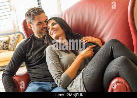 Glückliches Paar, das auf einem großen Sessel sitzt Stockfoto