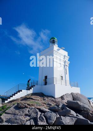 Südafrika, Westkap, St. Helena, eine Frau, die auf einen weißen Leuchtturm an der Küste klettert Stockfoto