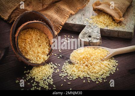 Braunes Reisgelb, für Risotto in Jute aus Leinensack auf einem Holzbrett Stockfoto