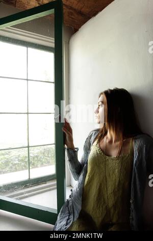 Junge Frau aus Fenster Stockfoto
