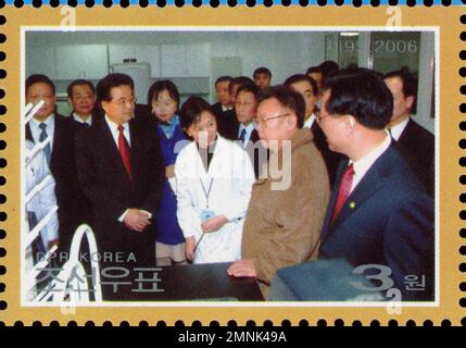 Nordkoreanische Briefmarke von 2006 mit Kim Jong-il bei einem offiziellen Besuch in einer Laboreinrichtung mit Regierungsbeamten. Stockfoto