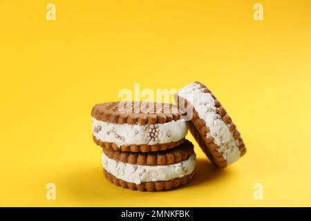Süße leckere Eis-Kekse-Sandwiches auf gelbem Hintergrund Stockfoto
