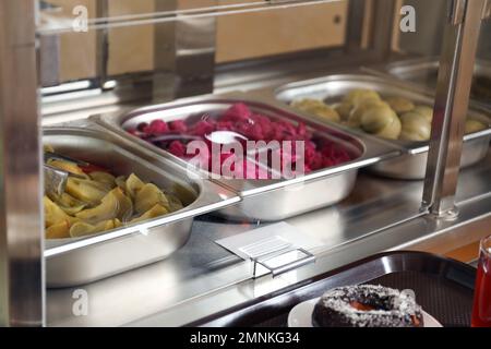 Behälter mit leckerem Essen in der Schulkantine Stockfoto