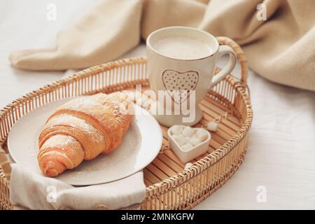 Köstlicher Morgenkaffee und Croissant auf dem Bett Stockfoto